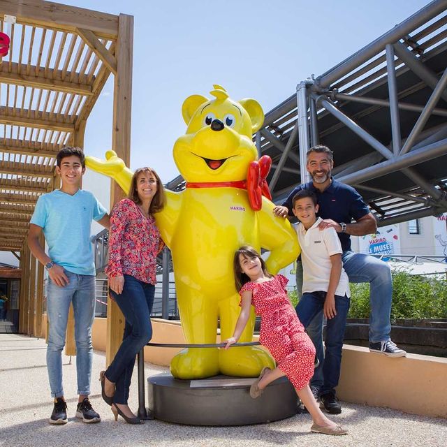 Famille au Musée du bonbon Haribo autour de la statue de l'ourson d'or